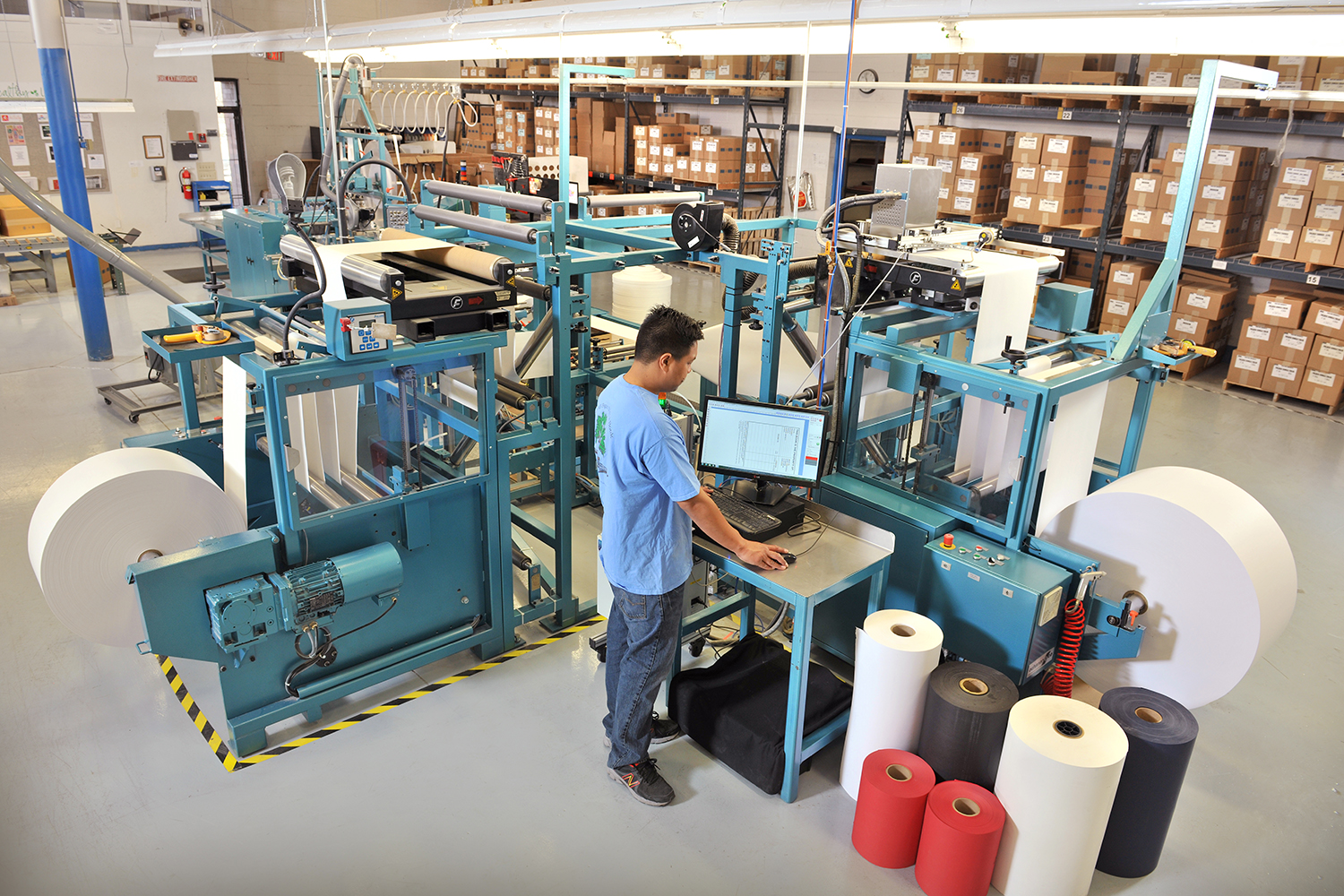 LBS employee standing at desk in front of computer in warehouse setting