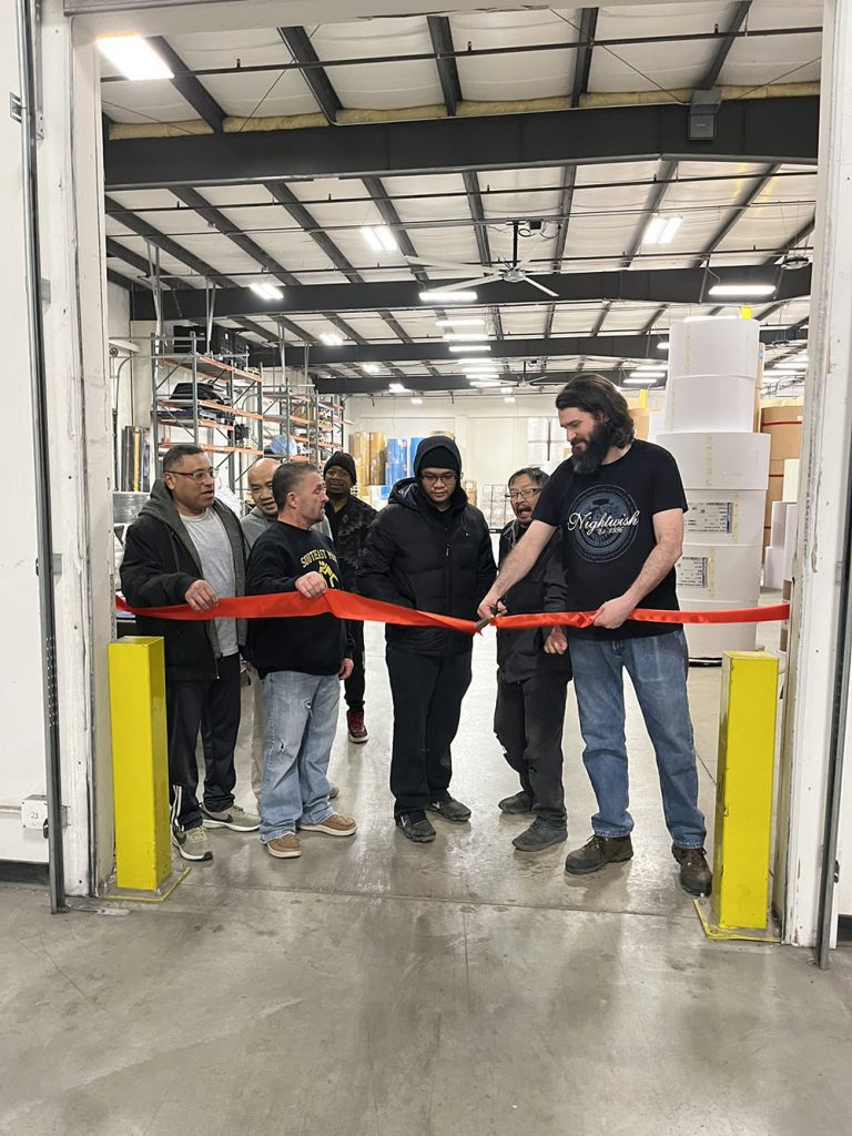 LBS employees cutting ribbon in warehouse